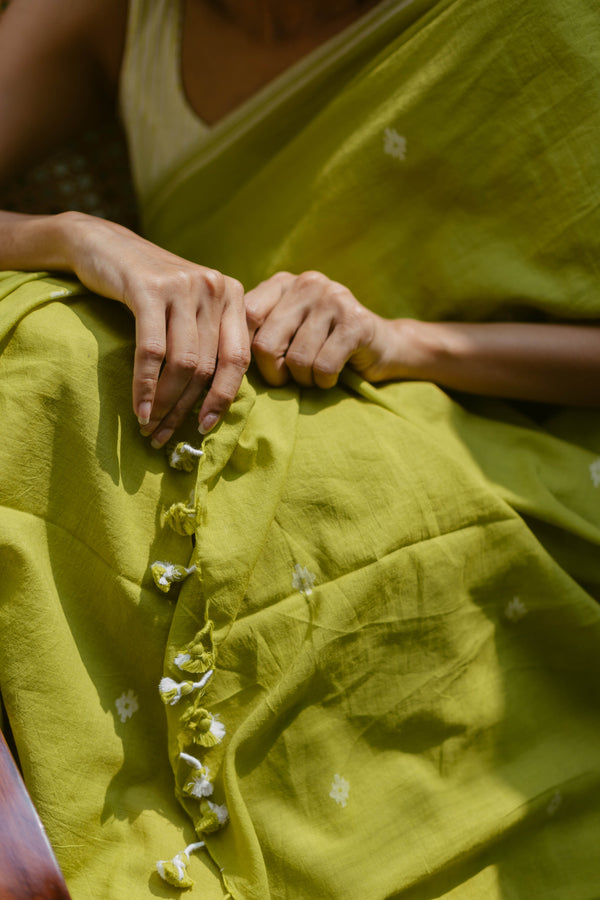 Elegant lime green Jamdani cotton saree with white border styled for a casual outdoor look.